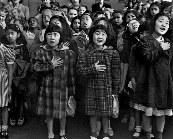 Second generation Japanese Americans Helene Nakamoto Mihara,7, and Mary Ann Yahiro,7, reciting the Pledge of Alligence the Raphael Weill School in San Francisco, California before they were sent to the Topaz Internment Camp during WWII. photographed by Dorothea Lange April 1942.